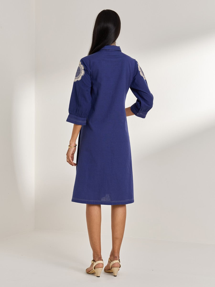 Blue cotton flax dress with embroidered motifs — structured and